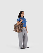 A woman wearing a BAGGU Cloud Bag in Photo Forest over her shoulder 