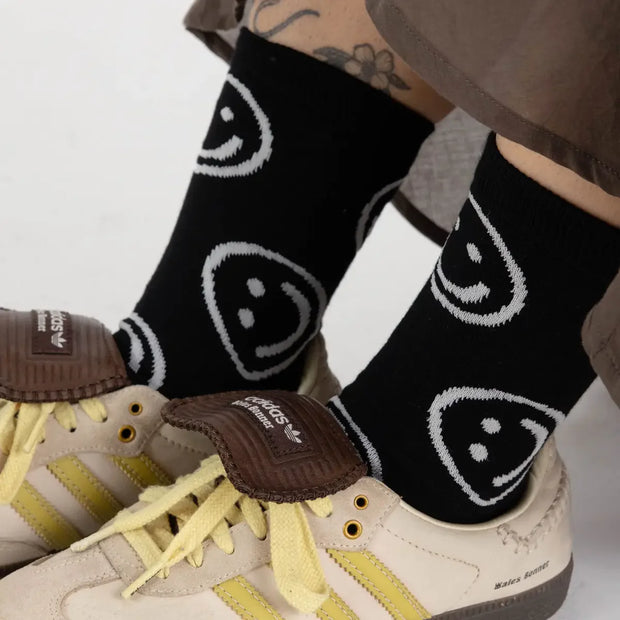 A person wearing a pair of BAGGU crew socks in Black Happy 