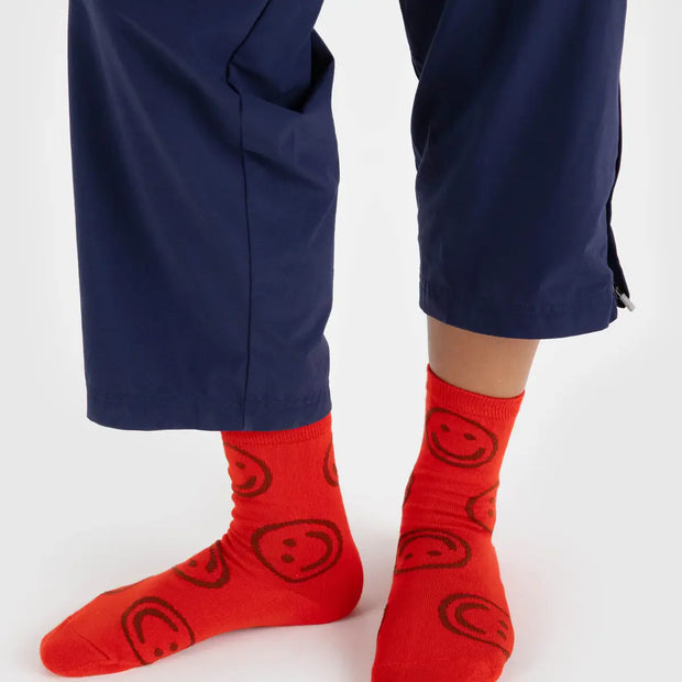 A person wearing a pair of BAGGU crew socks in Red Happy 2