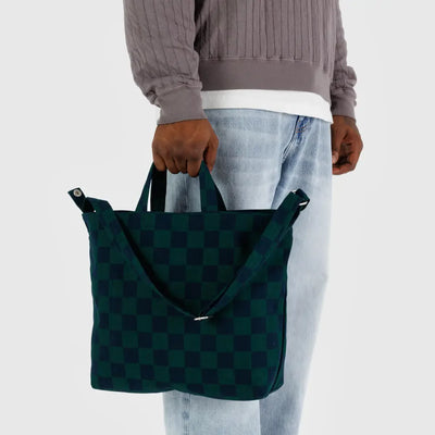A close up of a person holding a horizontal zip duck bag from BAGGU in Navy Green Check