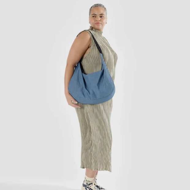 A woman holding a A large Crescent Bag from Baggu in Digital Denim