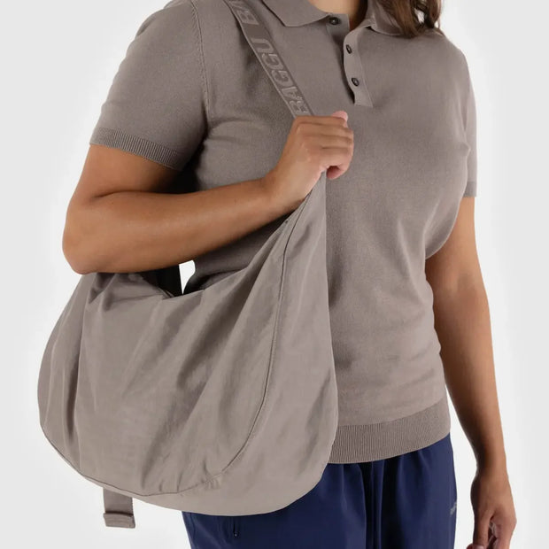A person wearing a large Crescent Bag from BAGGU in Dove