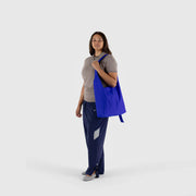 A person holding a large Nylon Sling bag from BAGGU in Lapis