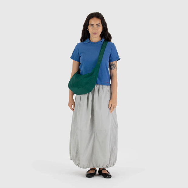 A woman wearing a BAGGU medium crescent bag in Cypress
