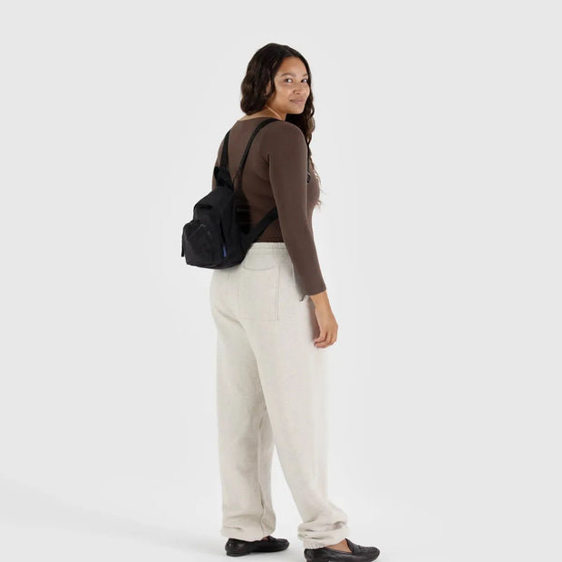 A mini recycled nylon backpack from BAGGU in Black worn shown across both shoulders