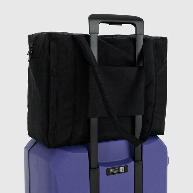 A small Cloud carry-on from BAGGU in Black shown on a suitcase