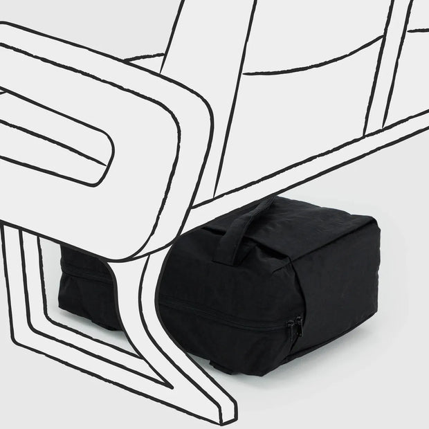 A visual image of the small Cloud carry-on from BAGGU in Black shown under an aeroplane seat