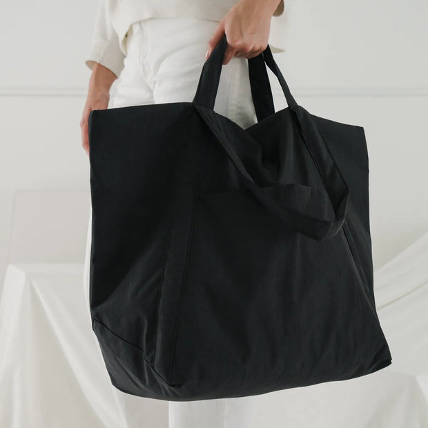 A BAGGU Travel Cloud bag being held by a person wearing white