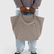 A person holding A BAGGU Travel Cloud bag in Dove, made from recycled heavyweight nylon