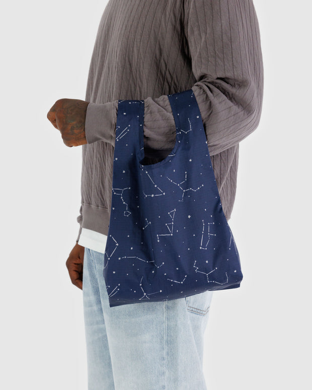 A person holding a Constellation Midnight Baby BAGGU