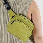 A close up of a person wearing a BAGGU bumbag or fanny pack crossbody in Lemongrass