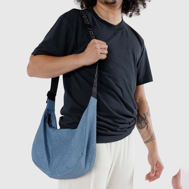A person holding a Baggu medium Crescent Bag in Digital Denim