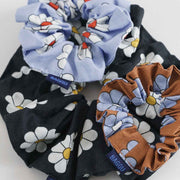 A set of three Baggu hair scrunchies in Daisies design stacked on top of each other