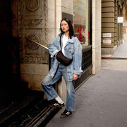 A lifestyle photo of a person wearing a small Crescent Bag from Baggu in Black crossbody