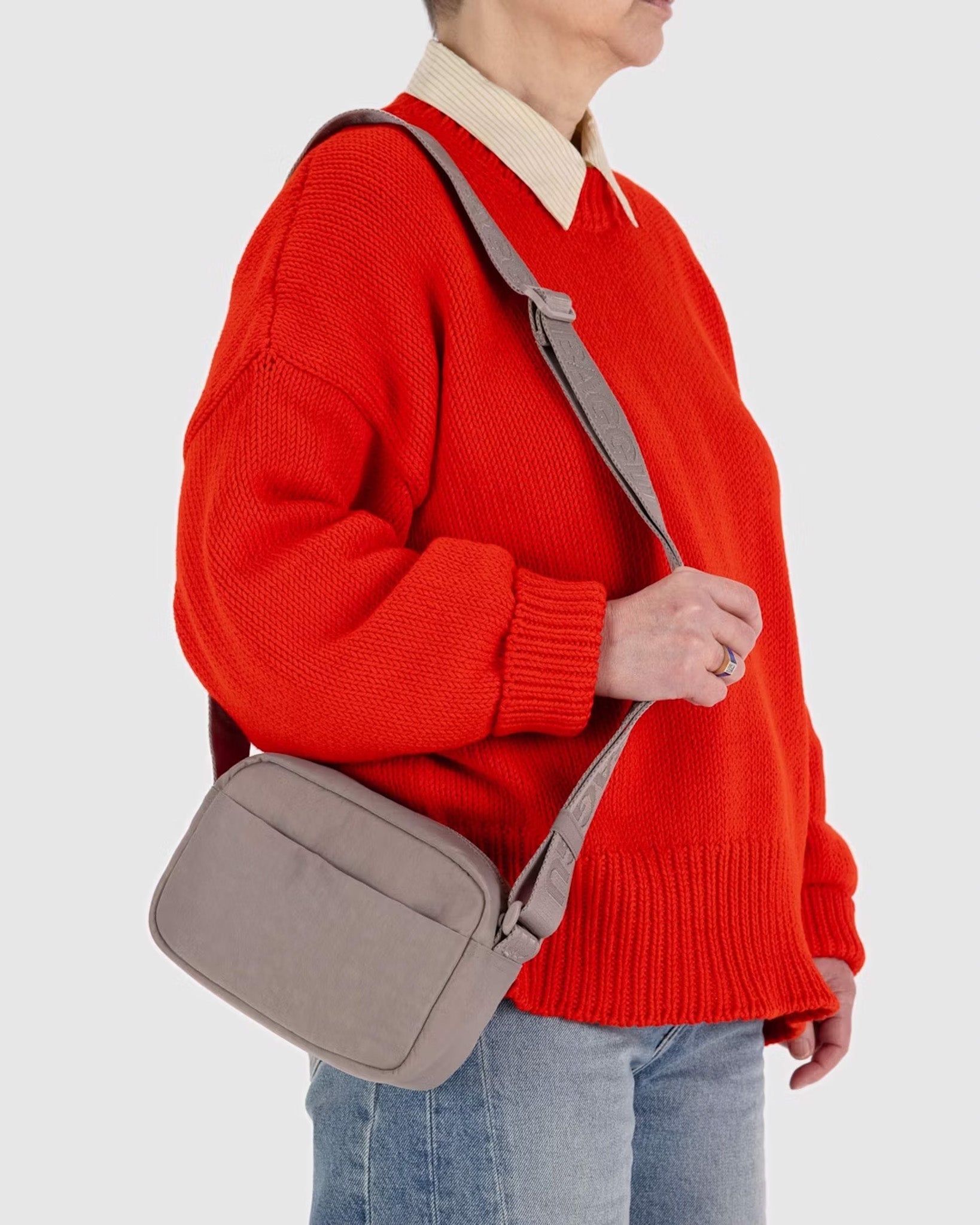 A person holding a BAGGU Camera Crossbody in Dove