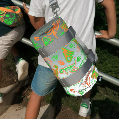 A boy wearing a LOQI kids dinosaur reflective mini weekender on their back