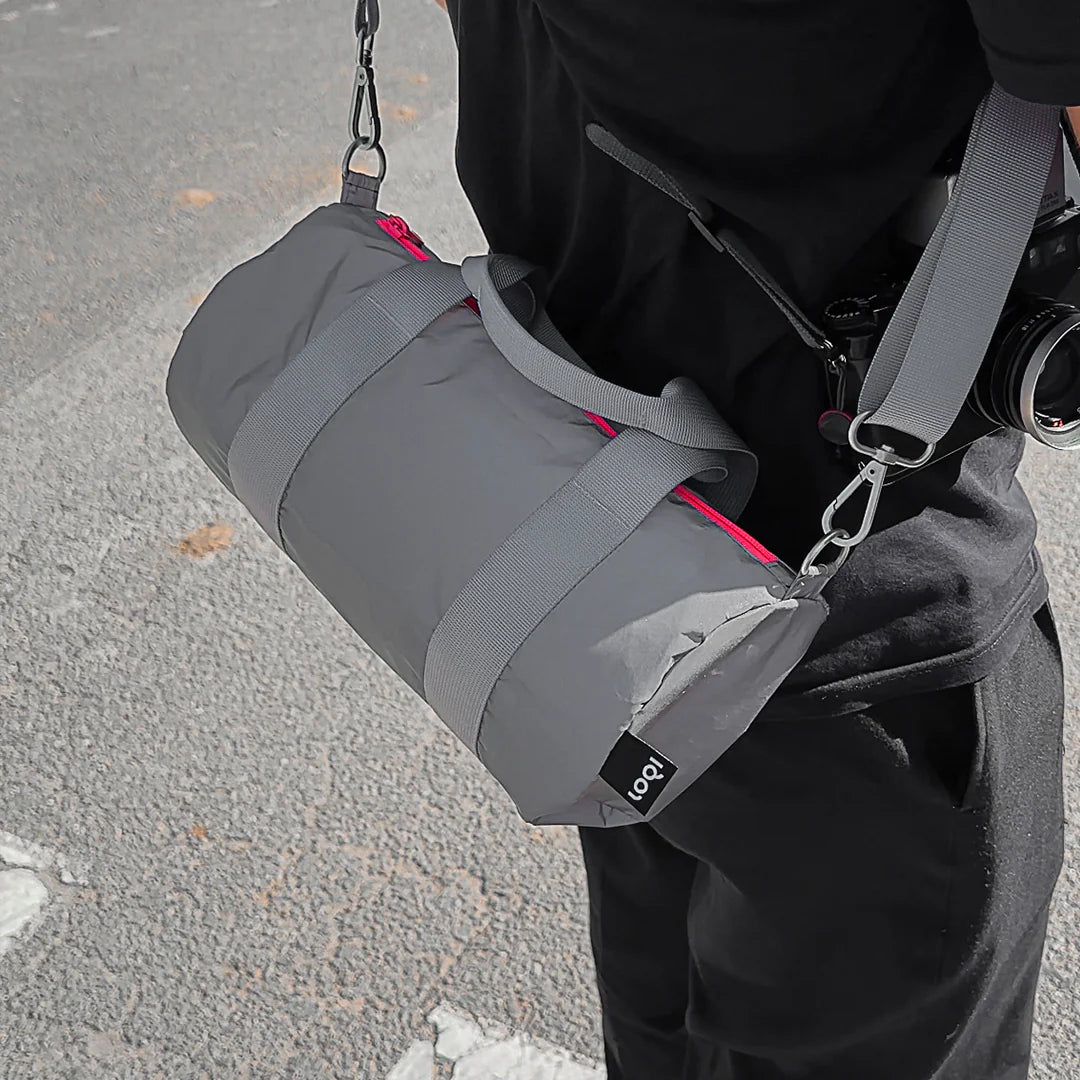 A person wearing a reflective Neon Dark Orange Mini Weekender from LOQI