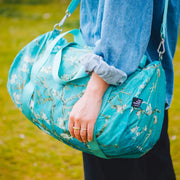 A person holding a LOQI weekender bag featuring the Almond Blossom artwork by Vincent Van Gogh x LOQI weekender bag. The colour is light blue with Van Gogh.