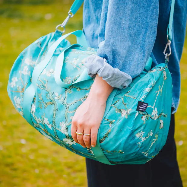 A person holding a LOQI weekender bag featuring the Almond Blossom artwork by Vincent Van Gogh x LOQI weekender bag. The colour is light blue with Van Gogh.