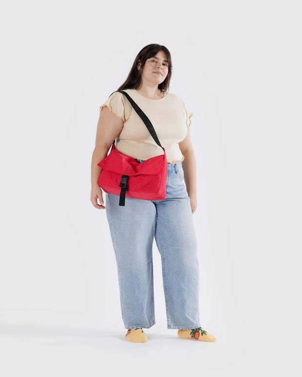 A person wearing a Baggu Recycled Nylon Messenger Bag in Candy Apple over their shoulder