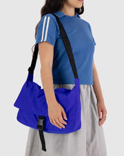 Close up of a person holding a BAGGU nylon messenger bag in Lapis